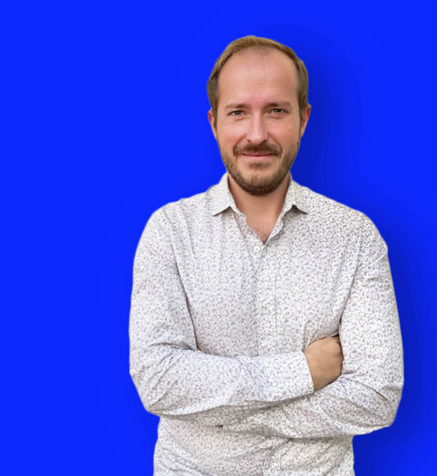 Foto de Joaquín Ruiz de medio cuerpo con los brazo cruzados y fondo azul